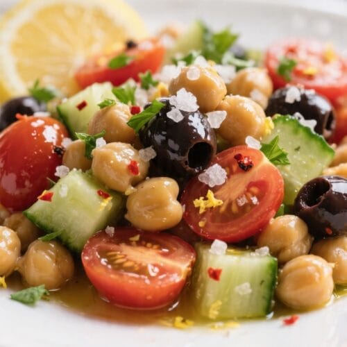 Close-up detail: Glossier-than-glossy chickpeas tossed with diced English cucumber, halved cherry tomatoes. Mediterranean chickpea cucumber salad