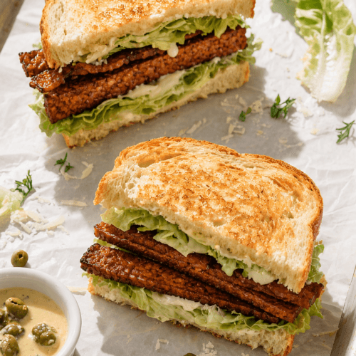 Tempeh Bacon Caesar Sandwiches: Savory, crunchy vegan sandwiches with fresh lettuce, capers & herb garnish—great for healthy lunches. Save this idea so you can come back to it later.