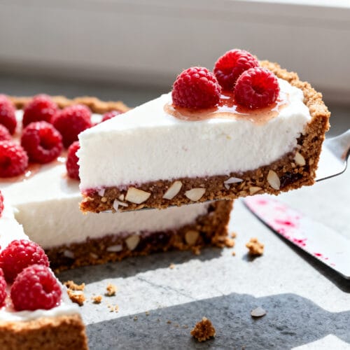 Close-up detail: A slice of no-bake vegan raspberry & coconut cream tart just lifted from the pan, s